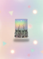 Earrings on a card with text 'I'm fine, it's just my face' against a light background