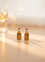 Jack Daniel's bottle-shaped earrings on a display card with a wooden stand.