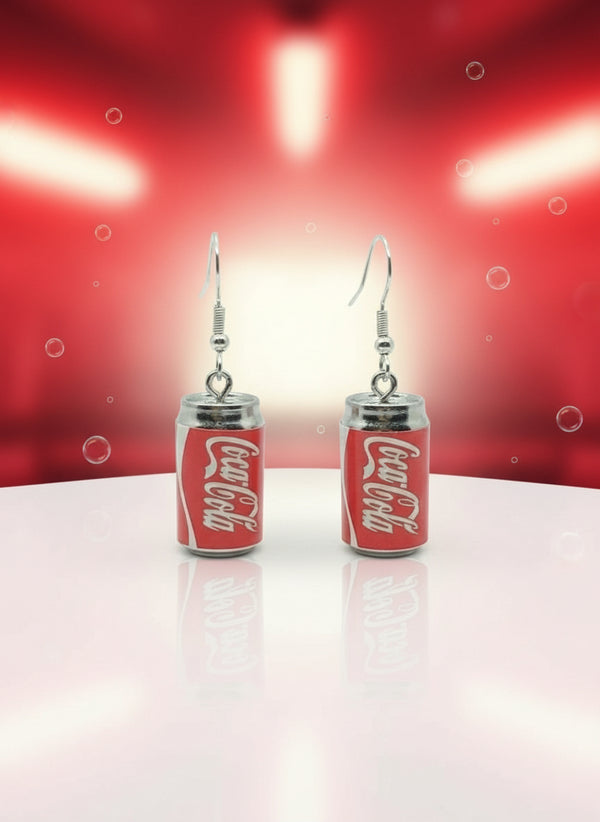 Coca-Cola can-shaped earrings on a black card with a wooden stand.