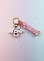 Keychain with mushroom charm and pink 'Happy Day' ribbon on a white background