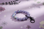 Silicone Wristlet Keychain featuring colorful beads on a lavender background, perfect for everyday use and gifts.