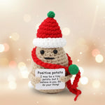 Emotional support crochet christmas potato with wooden stand wearing a red scarf and santa hat holding a positive message.
