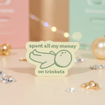 spent all my money on trinkets sticker displayed among decorative gems and soft pastel backgrounds