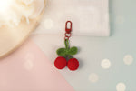 Crochet cherry keychain - handmade bag charm by Craft-N-Crumble® with red cherries and green leaves.