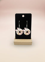 Cute Animal Donut Earrings displayed on a stand, featuring colorful animal faces in donut designs.
