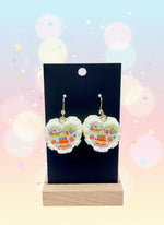 Mini Resin Cake Earrings displayed on a black stand against a colorful background, showcasing intricate dessert details.