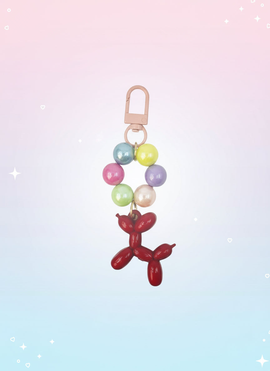 Keychain with colorful beads and a red balloon dog charm on a white background