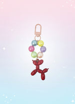 Keychain with colorful beads and a red balloon dog charm on a white background