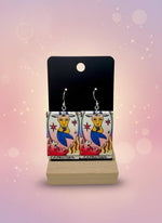 Earrings with Capricorn zodiac design on a display card against a white background