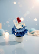 Mini Crochet Christmas Tree Ornament in blue and white yarn with colorful pom-poms, perfect for holiday decor.