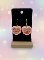 Mini Resin Cake Earrings displayed on a black earring stand with decorative cake design in pink resin.
