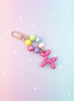 Keychain with colorful beads and pink balloon dog charm on a white background