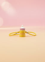 Yellow straw with a bottle-shaped charm on a white background