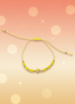 Yellow beaded bracelet on a cardboard holder against a white background