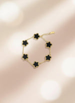 Bracelet with black flower-shaped ends on a cardboard holder against a white background