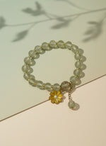 Beaded bracelet with a yellow flower charm on a white background