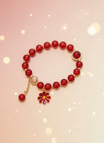 Red beaded bracelet with a gold charm on a white background