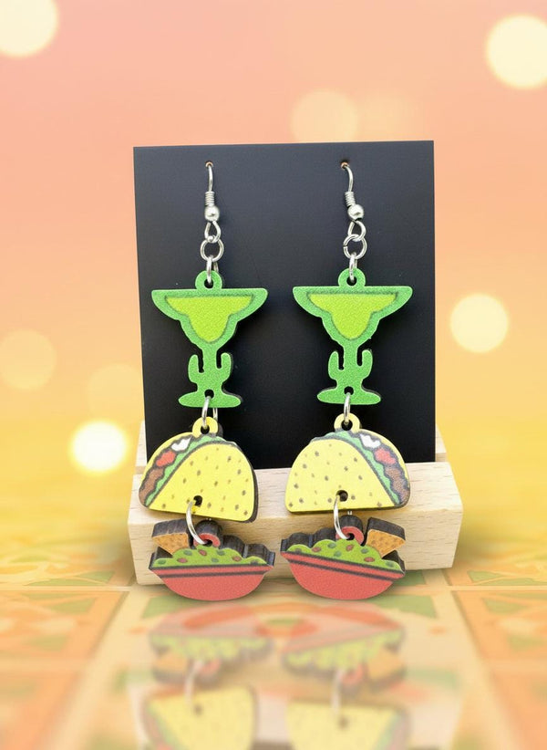 Colorful earrings shaped like tacos on a wooden stand with a black background