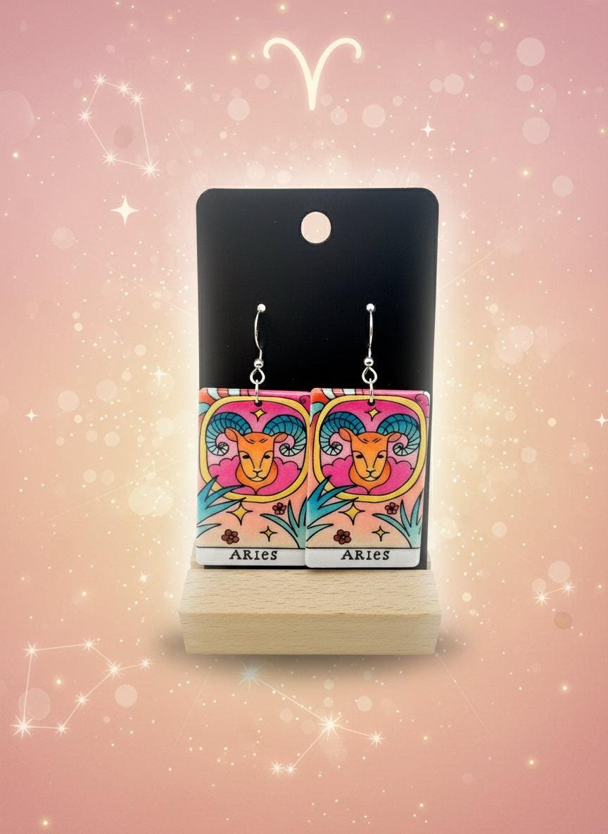 Aries zodiac earrings on a colorful card with a white background