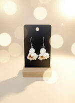 Popcorn-shaped earrings on a black card with a wooden stand against a white background