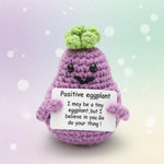 Positive Eggplant Crochet Doll with Wooden Stand, a cheerful handmade desk companion with a friendly expression.